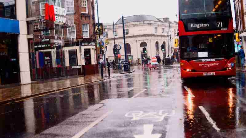 people walking on sidewalk during daytime - A London bus on a wet rainy road with reflections going from the Kingston town center next to the metro bank street., tags: verkauf - unsplash